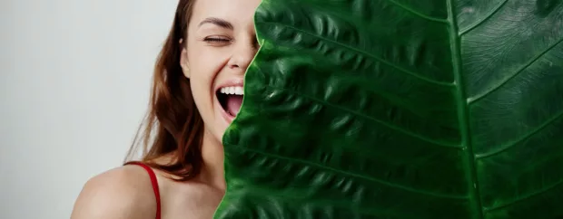 joyful woman covers her face with palm leaf Exotic close-up. High quality photo